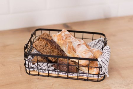 Photo for Fresh bread baguette in metal basket on a wooden table - Royalty Free Image