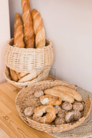 Photo for Wicker basket with bread and baguettes near beige wall background - Royalty Free Image