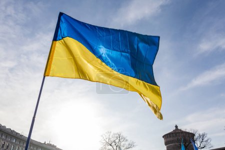 Foto de Bandera con colores a rayas amarillas y azules de Ucrania ondeando en el viento con un cielo azul y sol. - Imagen libre de derechos