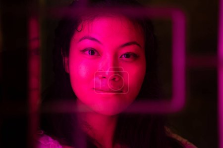 Téléchargez les photos : Gros plan portrait d'une femme asiatique souriante illuminée par des néons dans la nuit - en image libre de droit