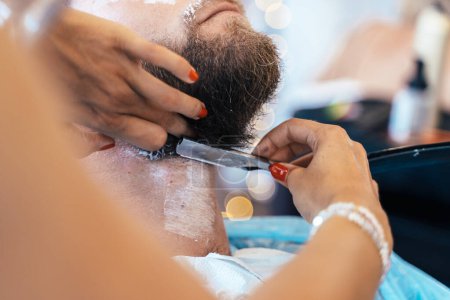 Photo for Cropped photo of an unrecognizable hairdresser shaving a client with a manual razor - Royalty Free Image