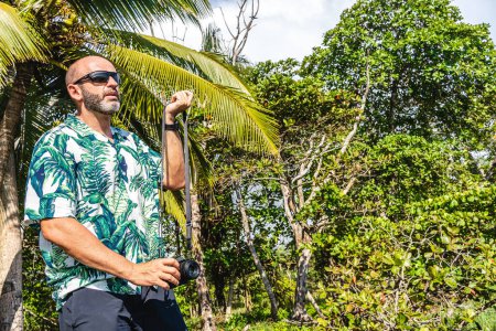 Téléchargez les photos : Photo avec espace de copie d'un homme avec un appareil photo numérique sur une forêt tropicale - en image libre de droit