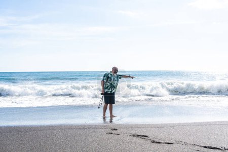 Photo for Panoramic photo with copy space of a man with a camera pointing ahead on the beach - Royalty Free Image