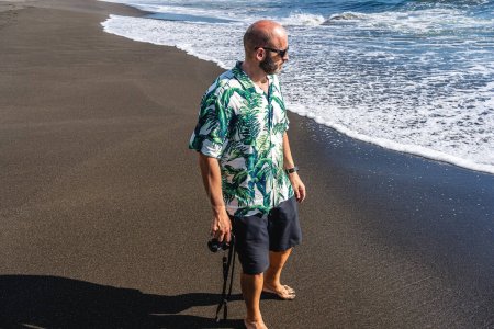 Téléchargez les photos : Vue de dessus d'un homme avec une caméra marchant le long de la plage - en image libre de droit