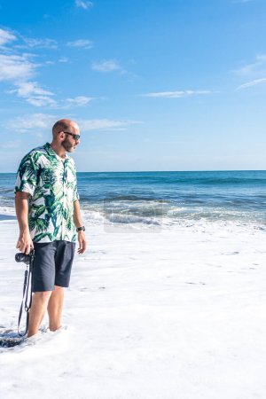 Foto de Foto con espacio de copia de un hombre con una cámara caminando por la playa - Imagen libre de derechos