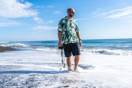 Foto de Foto con espacio de copia de un hombre con una cámara caminando por la playa - Imagen libre de derechos