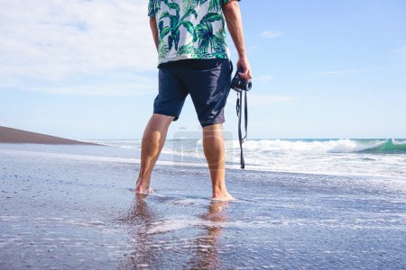 Foto de Foto recortada con espacio de copia de un hombre irreconocible con una cámara frente al mar - Imagen libre de derechos