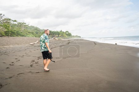 Foto de Foto con espacio de copia de un hombre caminando por una playa remota con una cámara - Imagen libre de derechos