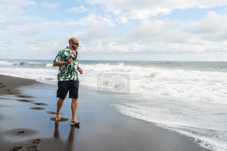 Foto de Foto con espacio de copia de un hombre caminando por una playa tropical con una cámara - Imagen libre de derechos