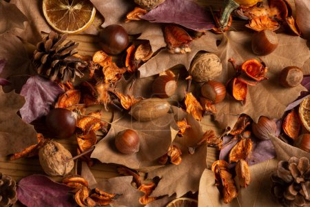 Overhead view of dried fruits, pumpkin and cinnamon with autumn leaves on wooden table, horizontal