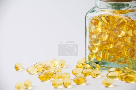 View of covered glass bottle with evening primrose oil pills, on white background with pills, horizontal, with copy space