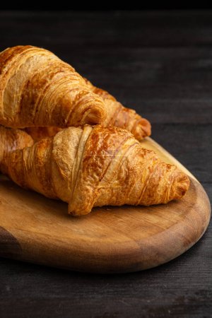 Photo for Top view of croissants on board on dark wooden table, vertical, with copy space - Royalty Free Image