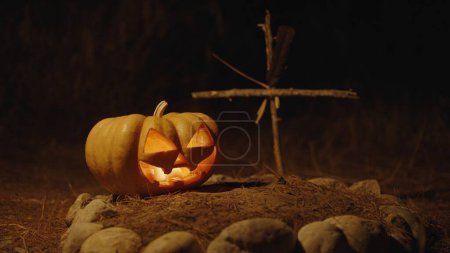 Foto de Calabaza de Halloween en la tumba rodeada de piedras. Noche, primer plano. - Imagen libre de derechos