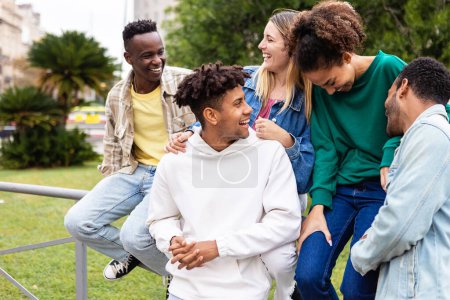 Foto de Happy multiethnic group of young friends having fun together outdoor. Friendship and community concept with multiracial teenager people hanging out in city street - Imagen libre de derechos