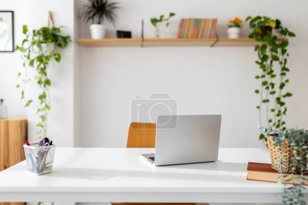 Téléchargez les photos : Ordinateur portable sur la table dans la pièce lumineuse de l'espace de travail de bureau à domicile - en image libre de droit