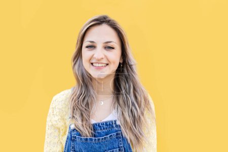 Photo for Cheerful portrait of young blonde girl looking at camera smiling over yellow background - Royalty Free Image