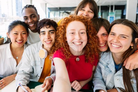 Photo for Multiracial group of young student people taking selfie while studying together sitting on table at cafeteria college campus. - Royalty Free Image