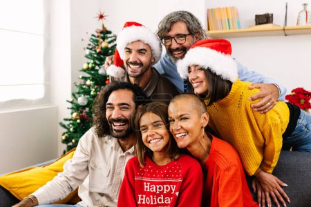 Photo for Smiling portrait of three generation family sitting together on sofa on christmas celebration. Grandfather, mother, father, son, daughter and grandchildren posing for photo. - Royalty Free Image