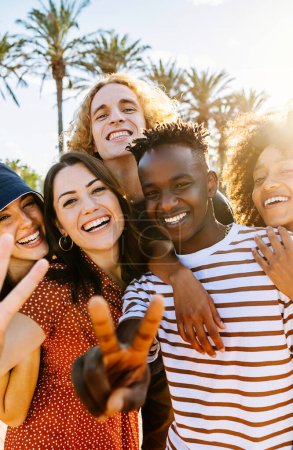 Photo for Vertical portrait group of young multicultural trendy friends looking at camera while standing by palm trees background. Outdoor photo of diverse happy people having fun in summer. - Royalty Free Image