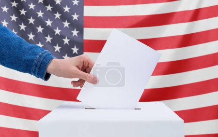Elecciones, Estados Unidos. Una mano humana lanza una papeleta a las urnas. Bandera americana en el fondo. Concepto electoral.