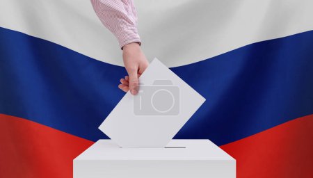 Wahlen, Russland. Das Konzept der Wahlen. Eine Hand wirft einen Stimmzettel in die Wahlurne. Russische Flagge auf dem Hintergrund.