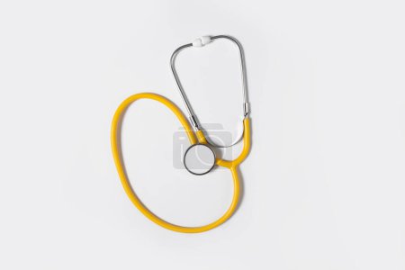 Gelbes Stethoskop auf hellem Hintergrund, Draufsicht. Medizinisches Instrument. Gesundheitstag.