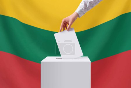 Elections, Lithuania. A hand throws a ballot into the ballot box. The flag of Lithuania on the background. Voting concept.