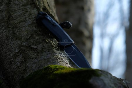 Foto de LVIV, UCRANIA - 27 de febrero de 2024: SOG Terminus cuchillo negro en el bosque sobre un fondo de madera. - Imagen libre de derechos