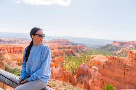 Hiker woman in Bryce Canyon resting enjoying view in beautiful nature landscape with hoodoos, pinnacles and spires rock formations. Bryce Canyon National Park landscape in Utah, United States. 