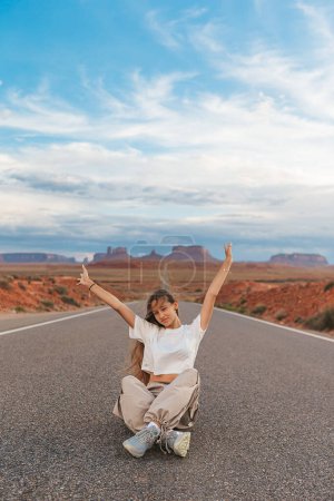 Happy girl leva la main sur la célèbre route de Monument Valley dans l'Utah. Vue imprenable sur la vallée du Monument.