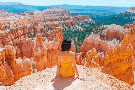 Téléchargez les photos : Femme heureuse en robe jaune sur le sentier dans un magnifique paysage naturel avec des hoodoos, des pinacles et des flèches formations rocheuses dans le parc national de Bryce Canyon, Utah - en image libre de droit