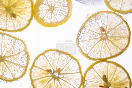 Foto de Jugosas rodajas de limón con burbujas bajo el agua aisladas sobre fondo blanco. Patrón de rodajas de limón amarillo fondo texturizado. - Imagen libre de derechos
