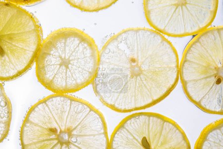 Foto de Jugosas rodajas de limón con burbujas bajo el agua aisladas sobre fondo blanco. Patrón de rodajas de limón amarillo fondo texturizado. - Imagen libre de derechos