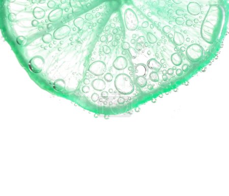 Foto de Jugosas rodajas de lima con burbujas bajo el agua aisladas sobre fondo blanco. Verde limón rodajas patrón texturizado fondo. - Imagen libre de derechos
