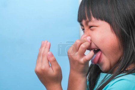Téléchargez les photos : Petite fille asiatique couvrant sa bouche pour sentir la mauvaise haleine. Enfant fille vérifier la respiration avec ses mains. Problèmes de santé buccodentaire ou concept de soins dentaires. - en image libre de droit