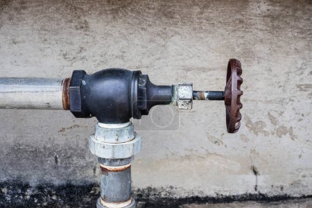 Rostige industrielle Wasserpumpe und Wasserhahn an der Wand