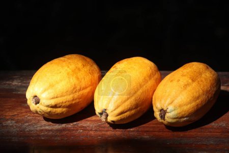 Photo for Three fresh cocoa fruits with cocoa pods on the tabletop - Royalty Free Image