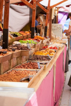 A bustling medieval market stall filled with a colourful assortment of dried fruits and nuts, inviting customers into a world of flavours