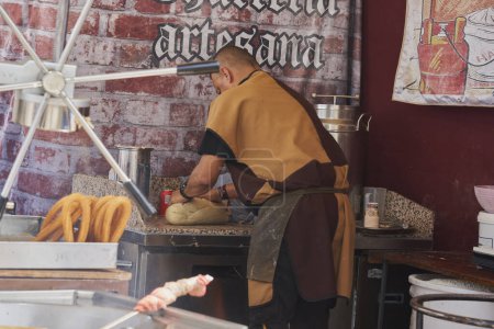 Handwerker bereitet den Teig zum Braten von Churros an seinem Stand auf einem Mittelaltermarkt zu