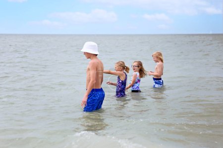 Téléchargez les photos : Un groupe familial d'enfants joue dehors dans l'eau sur une plage de Floride dans l'océan. - en image libre de droit