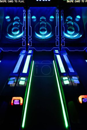 A close up photo on a skee-ball game at a video arcade lit up with blue and green neon lights.