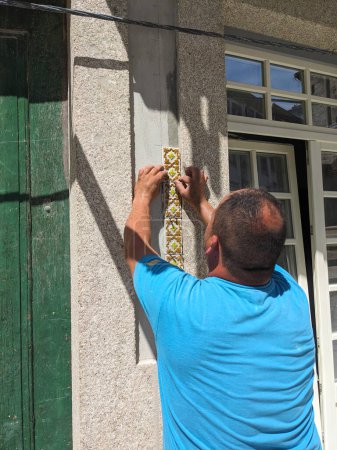 Der Bauunternehmer verlegt Azulejo-Fliesen an der Fassade eines Hauses in Porto, Portugal