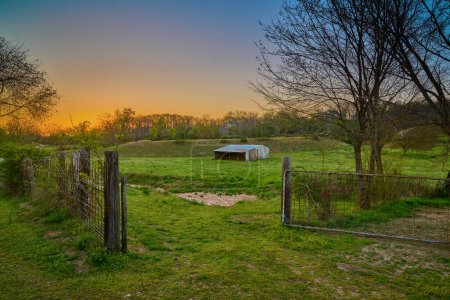 Photo for Sunset over a farm with old barn and gate near Bentonville Arkansas. - Royalty Free Image