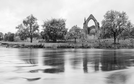 Téléchargez les photos : Longue exposition de l'eau qui coule rapidement sur le Wharfe passant devant l'abbaye de Bolton dans le Yorkshire photographiée en octobre 2022. - en image libre de droit
