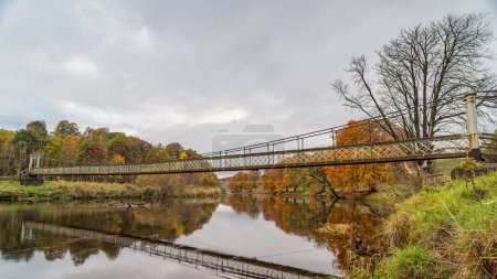 Foto de Colores otoñales rodean el puente colgante Hebden que cruza el río Wharfe en Yorkshire. - Imagen libre de derechos