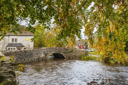 Téléchargez les photos : Pont de Malham vu enjambant le Malham Beck au cœur du Yorkshire Dales encadré par les arbres colorés de l'automne. - en image libre de droit
