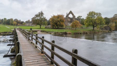 Téléchargez les photos : La longue passerelle en bois qui enjambe le Wharfe jusqu'à l'abbaye de Bolton, dans le Yorkshire, capturée en octobre 2022. - en image libre de droit