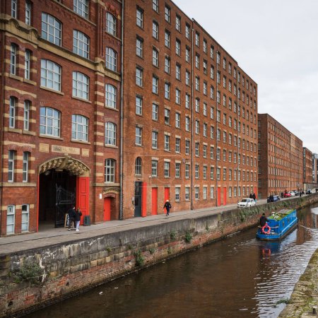 Téléchargez les photos : A blue narrow boat contrasts against the traditional red bricks of Royal Mill along Redhill Street in the Ancoats area of Manchester in February 2023. - en image libre de droit