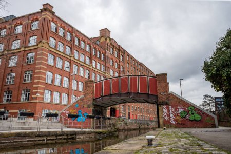 Téléchargez les photos : The iconic red Kitty Footbridge seen in front of the Royal Mill crossing the Rochdale canal in the Ancoats area of Manchester in February 2023. - en image libre de droit