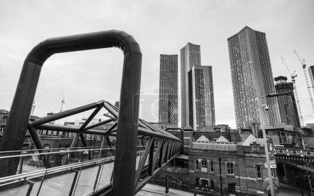 Téléchargez les photos : A black and white image of the Deansgate Square skyscraper complex pictured over the Deansgate Castlefield footbridge in Manchester in February 2023. - en image libre de droit